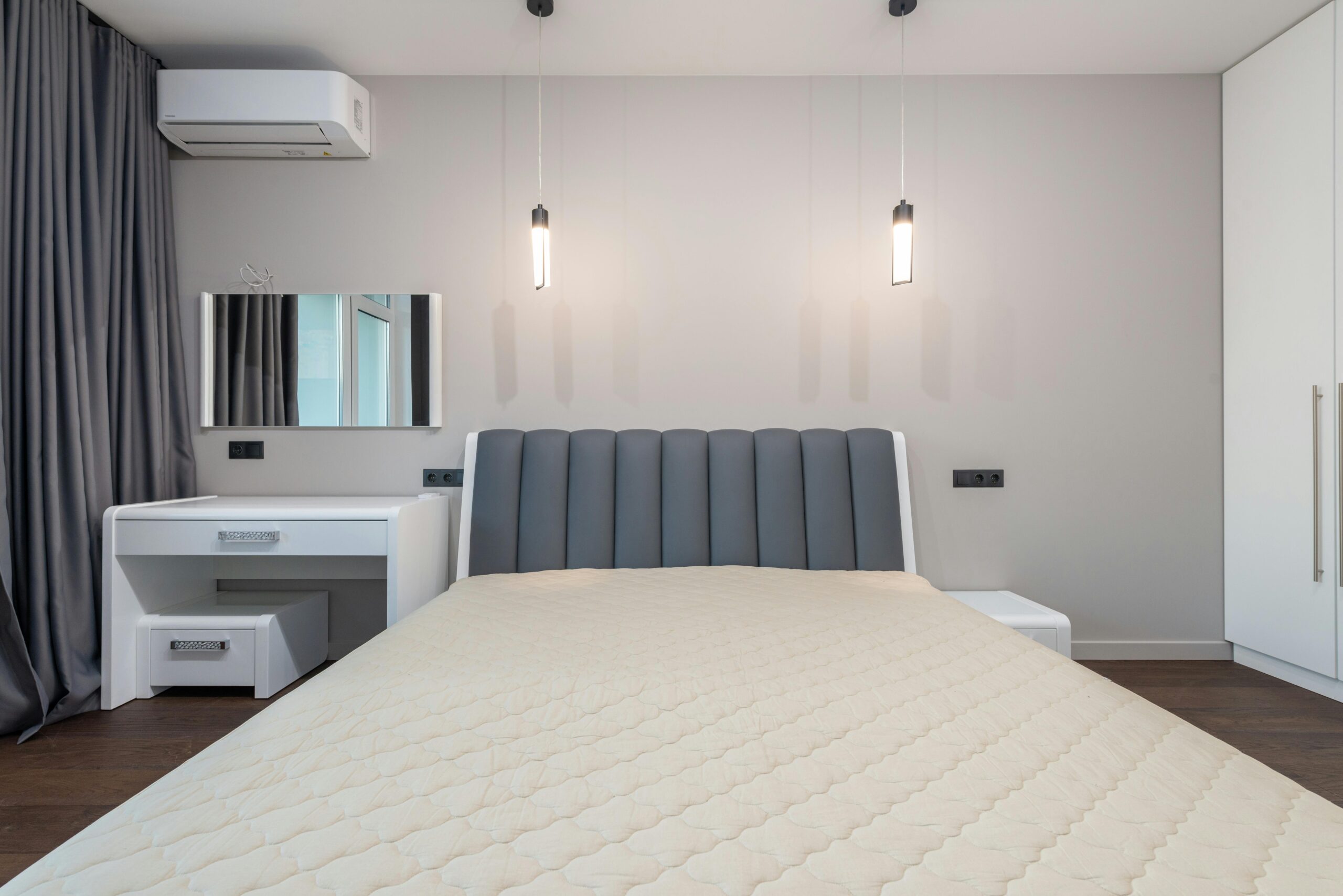 Sleek minimalist bedroom design featuring a plush bed, pendant lighting, and modern furnishings.
